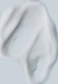 Weiße, cremige Textur mit glänzender Oberfläche und Bläschen. Wellenförmige Struktur mit sanften Kanten. Lichtreflektierendes, glattes Aussehen.