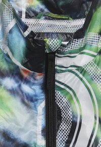 Letvægts, multikolor vindjakke med en blanding af blå, grøn og sort mønster, mesh-foret og en frontal lynlås.