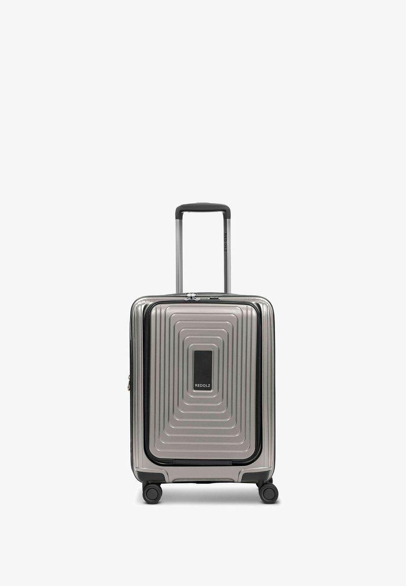 Valigia rigida da cabina in argento, caratterizzata da una texture a righe, un pannello di accentuazione nero e un manico estraibile con quattro ruote.