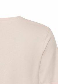 Jasnoróżowa koszulka z krótkim rękawem i okrągłym dekoltem. Miękka tkanina o gładkiej fakturze; prosty, czysty design, bez widocznych wzorów czy akcentów.
