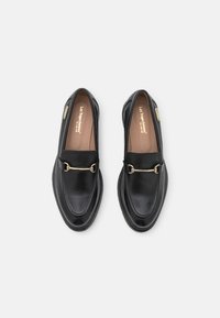 Zwarte leren loafers met amandelvormige neus, voorzien van een goudkleurige kettingaccent. Gladde textuur met gestikte details op de bovenkant.