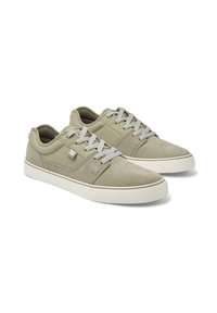 Green suede sneakers with gray laces, rounded toe, textured accents, and a white rubber sole. Features a logo patch on the side.