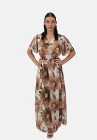 Robe maxi fleurie en tissu léger, avec un col en V, de courtes manches volantées et une taille élastique; les couleurs incluent beige, marron et vert.