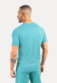 Maglietta sportive a maniche corte color turchese con scollatura rotonda e maniche raglan, realizzata in un tessuto leggero e morbido.