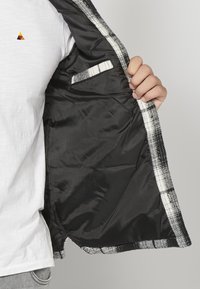Zwart-wit geruite blazer, met een gladde satijnen voering, een binnenzak en een slanke pasvorm.