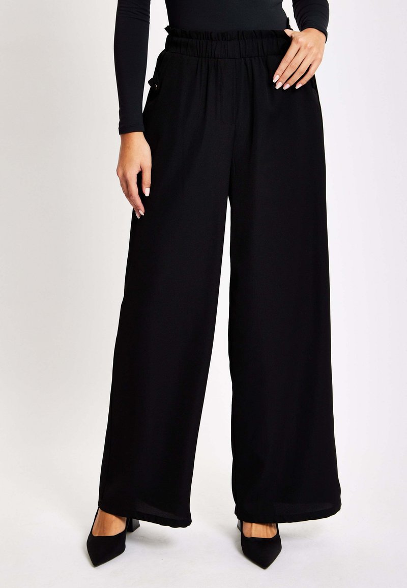 Black wide-leg trousers made of lightweight fabric, featuring a ruffled waistband, side pockets, and smooth texture.