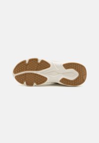 White athletic shoe outsole with a textured brown rubber pattern, featuring an ergonomic design and curved edges for optimal grip.