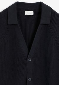 Cardigan tricoté marine avec un col en V, un petit col et deux boutons sur le devant. Tissu texturé avec des accents côtelés.