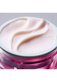 Creamy, pale pink moisturizer in a clear jar with a pink base, featuring a smooth surface with gentle wave patterns.