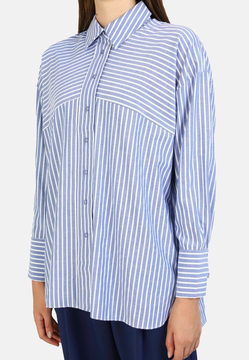 Camicia button-up di un blu chiaro con strisce verticali bianche, dotata di colletto, maniche lunghe e orlo dritto, realizzata in un tessuto morbido.