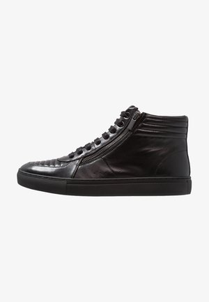 Basket montante en cuir noir avec fermeture éclair latérale, bout rond, matelassage rembourré au talon et à l’orteil, et semelle en caoutchouc noire.