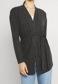 Långärmad cardigan i mörkgrått stickat tyg, med V-ringning, knytbälte i midjan och öppen framsida. Avslappnad passform.