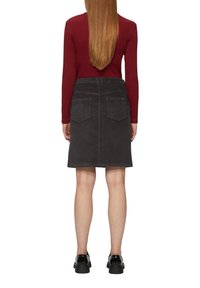 Jupe en velours côtelé gris avec une coupe droite, deux poches arrière et une ceinture. Associée à un haut à manches longues bordeaux et des chaussures noires.