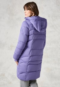 Cappotto puffo viola con cappuccio, caratterizzato da un design trapuntato, polsini a coste e un logo sulla manica sinistra. Taglio di lunghezza media. Tessuto liscio.
