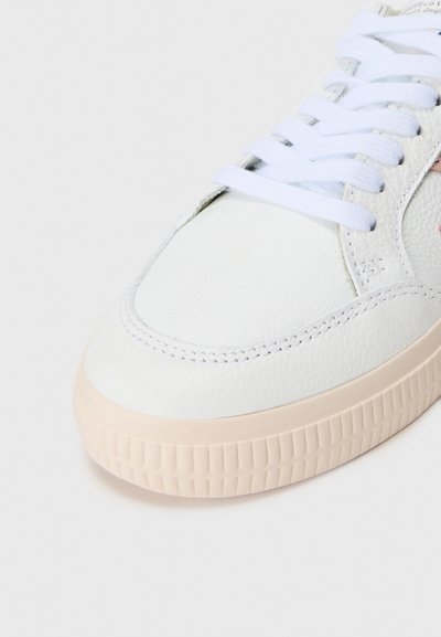 Tenis alb din piele cu un design neted, vârf rotund, șireturi albe și o talpă din cauciuc texturată în nuanță de bej. Accente laterale vizibile.