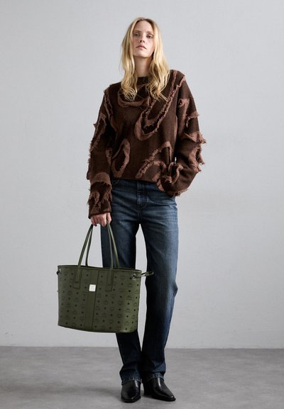 Brown, distressed sweater with textured patches, paired with blue jeans and a green tote featuring a subtle pattern and two handles.