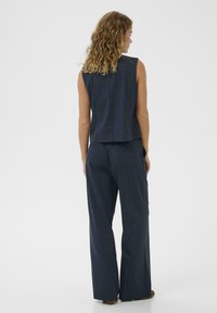 Tengerészes csíkos, ujjatlan felső egyenes szabással, amelyhez passzoló, bőszárú nadrág tartozik, sima anyaggal és visszafogott textúrával.