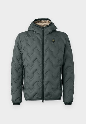 Giacca imbottita verde scuro con cappuccio, caratterizzata da una chiusura con zip, riprese a zigzag e polsini elasticizzati. Foderata con un materiale beige a contrasto.