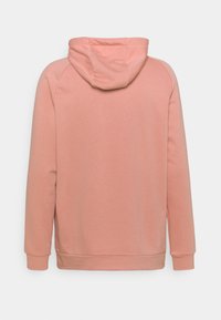 Sweat à capuche en tissu rose doux, avec manches longues, poignets côtelés et poche kangourou. Texture lisse avec coutures minimales.