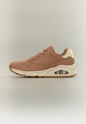 Brun og beige Skechers sneaker med snøre foran og synlig luftdæmpning i sålen, vist fra siden på en ensfarvet lys baggrund.