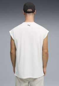 T-shirt blanc sans manches avec un col rond et un discret logo Puma noir au dos. Tissu doux avec une coupe décontractée, présenté de dos.