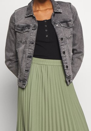 Chaqueta de mezclilla gris con cierre de botones, dos bolsillos frontales, combinada con una camiseta negra de canalé y una falda plisada verde claro.