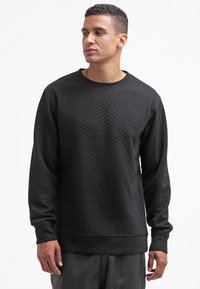Czarny pikowany sweatshirt z długimi rękawami, okrągłym dekoltem i teksturowaną powierzchnią. Posiada luźny krój oraz ściągacze na nadgarstkach.