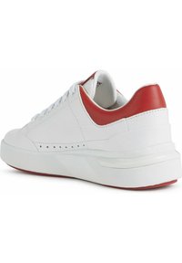 Bílé kožené tenisky s červeným akcentem na patě, hladkým povrchem a perforovanými detaily. Tlustá bílá podrážka s červeným podkladem.