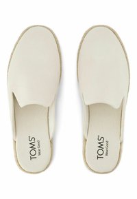 Krémově zbarvené nazouvací boty s hladkým svrškem, zaoblenou špičkou a podrážkou ve stylu jutového vlákna. Na stélce se nachází značka "TOMS".