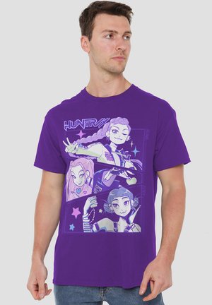 Purple cotton t-shirt featuring a graphic design of three animated characters with stars and text, set against a contrasting background.