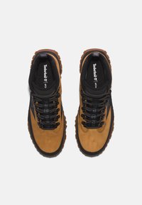 Zapatos de senderismo para hombres, de cuero marrón de Timberland, con acentos en negro, suelas gruesas con buen agarre, cuellos acolchados en negro y cordones negros con patrón.