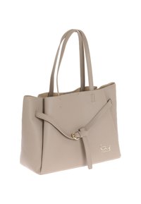 Beige leren tote bag met een textuur oppervlakte, voorzien van een goudkleurige accenten en een strikdetail aan de strap. Dubbele handgrepen voor draaggemak.