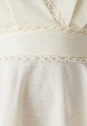 Vestido hasta la rodilla en un suave tejido crema texturizado, con una cinturilla tejida y detalles en forma de bucle, que presenta un escote en V y un diseño drapeado.