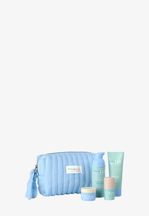 Lichtblauw gewatteerd cosmetisch tasje met vier bijpassende huidverzorgingsproducten waaronder schuimende gezichtsreiniger, crème, tube wasgel en lippenbalsem.