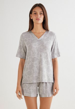Grå kortärmad V-ringad topp och matchande shorts med blommönster. Slät textur, avslappnad passform och något uppvikta ärmar.