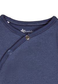 Blaues geripptes Stoffoberteil mit V-Ausschnitt, ausgestattet mit einem Druckknopfverschluss und kontrastierenden Nahtdetails. Das Markenetikett ist am Hals sichtbar.