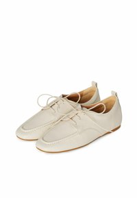 Beige nahkasaappaat nauhoilla, pyöristetyn kärjen, ommellun reunuksen ja tasapohjan kanssa. Liukas pinta ja minimaalinen yksityiskohtaisuus sivuilla.