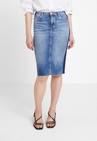Denim pencil skirt in light blue with a frayed hem, featuring a dark blue side panel and five belt loops. Paired with strappy black heels.