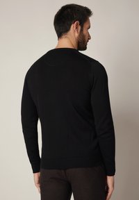 Czarny sweter z okrągłym dekoltem, ściągaczami na mankietach i dolnym brzegu, gładką fakturą oraz prostym wzornictwem. Brak widocznych logo lub wzorów.