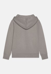 Siva kapucna majica z gladko teksturo, kenguru žepom in rebrastimi manšetami. Ima sproščen kroj in preprost, minimalističen dizajn.