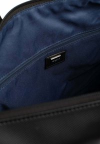 Zwarte binnenkant van een tas met een gladde marineblauwe voering, met een ritscompartiment en een klein zwart label met witte tekst.