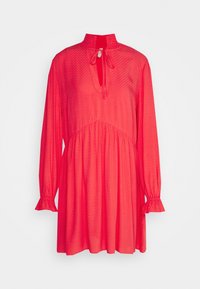 Robe à manches longues de couleur rouge vif avec taille froncée, col montant avec lien, motif texturé subtil et poignets à volants sur un fond uni.