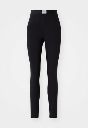 Leggings neri con una texture liscia e un vasto elastico in vita, dotati di un piccolo logo rettangolare. Design semplice senza motivi o decorazioni.