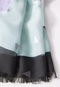 Sciarpa leggera color verde menta, con accenti triangolari in argento e bordo nero. Le estremità sfilacciate aggiungono texture e dettaglio.