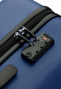 Maleta rígida azul con una superficie texturizada, cremallera negra y un candado aprobado por la TSA con tres diales para mayor seguridad.