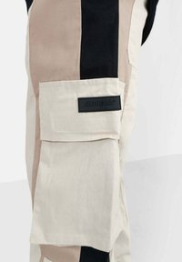 Cargo pants met een patch pocket, voorzien van zwarte, beige en crèmetinten. Inclusief een gestructureerd merkembleem in het zwart op de zak.