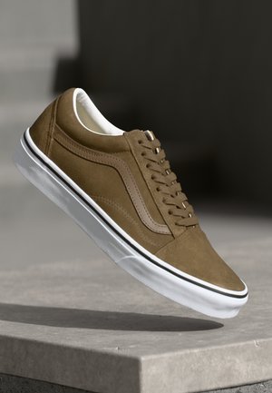 Brown suede sneaker with white rubber sole, featuring a classic lace-up design and a side swoosh detail in a lighter brown shade.