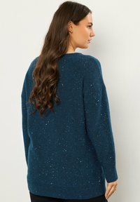 Türkis gestrickter Pullover mit lockerer Passform, ausgestattet mit einem gesprenkelten Design, gerippten Bündchen und Saum. Weiche Textur und ärmel in mittlerer Länge.