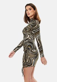 Long-sleeve dress in a swirled black, white, and gold pattern; features ruching on the side and drawstring detail at the hem.