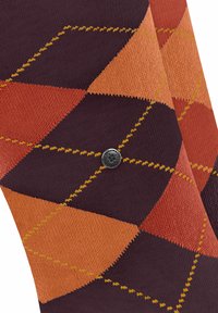 Chaussettes montantes de couleur marron et orange à motif argyle, avec des coutures jaunes et un petit bouton logo noir en détail.